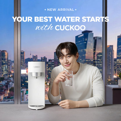 Cuckoo water purifier promotional image with text 'NEW ARRIVAL' and 'YOUR BEST WATER STARTS with CUCKOO'. Features a white counter top water purifier and a man smiling while holding a glass of water against a city night view background